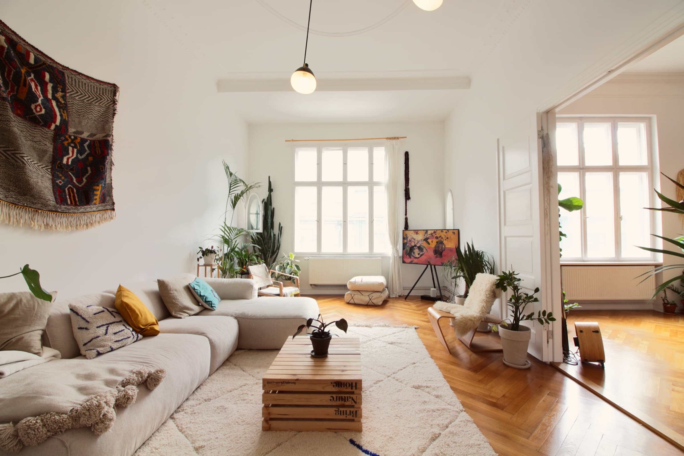 Helles Wohnzimmer mit Fischgrätparkett, Sofa und Zimmerpflanzen in der Altbau Location Berlin